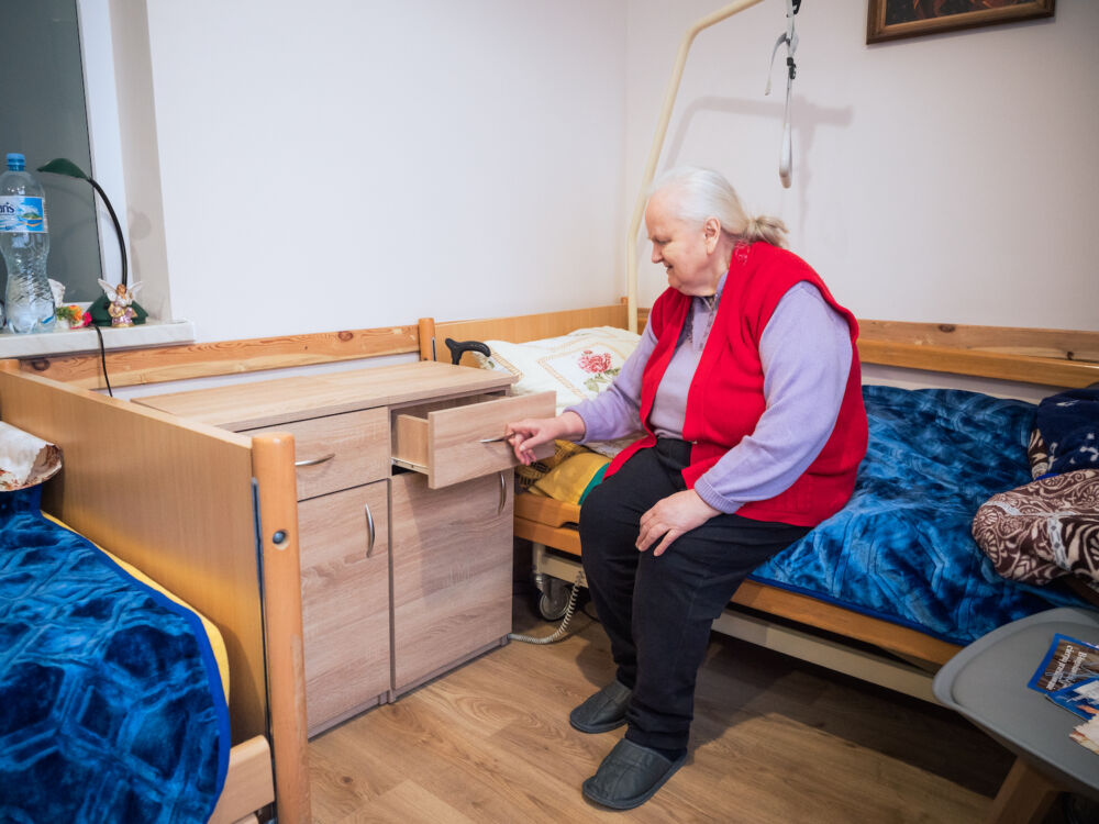 Une résidente de la Maison d'accueil de Przeworsk inspecte la nouvelle table de nuit que les volontaires de Ouest-Est viennent d'installer dans sa chambre.