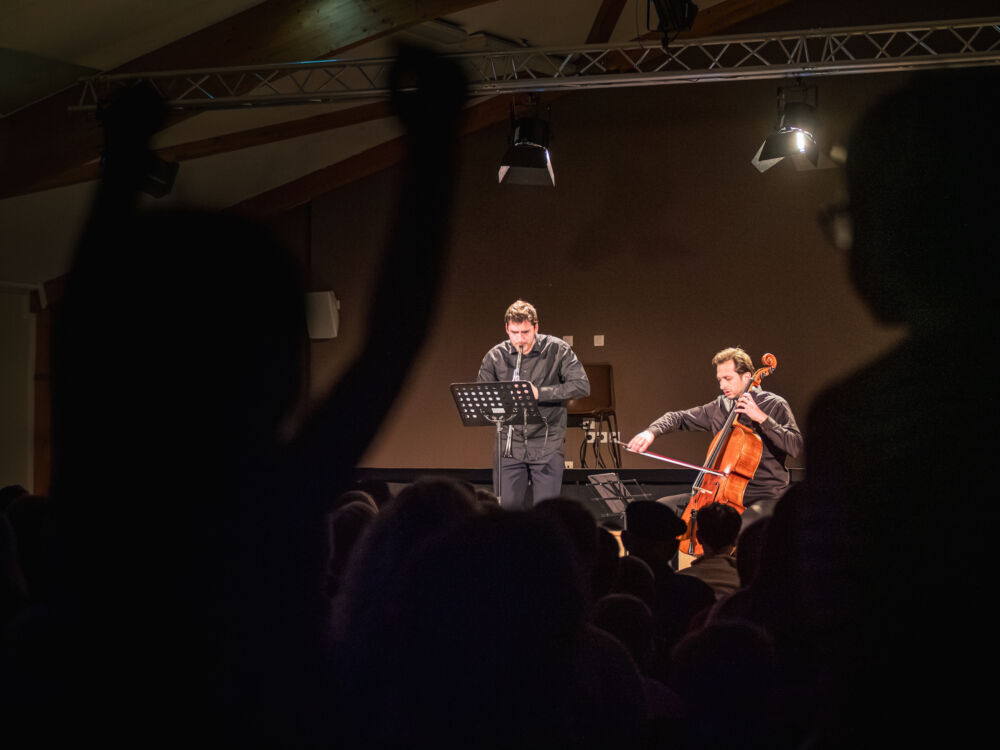 Dans la salle, le frère d'une des membres de la chorale des enfants écoute attentivement, pendant que sa petite soeur fait des entrechats sur sa chaise.