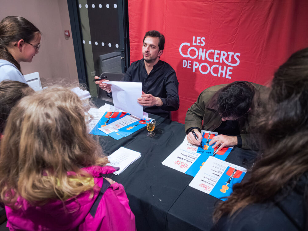 Après le concert, les deux artistes dédicacent des affiches de la soirée pour les enfants avec qui ils ont partagé la scène pendant la soirée.