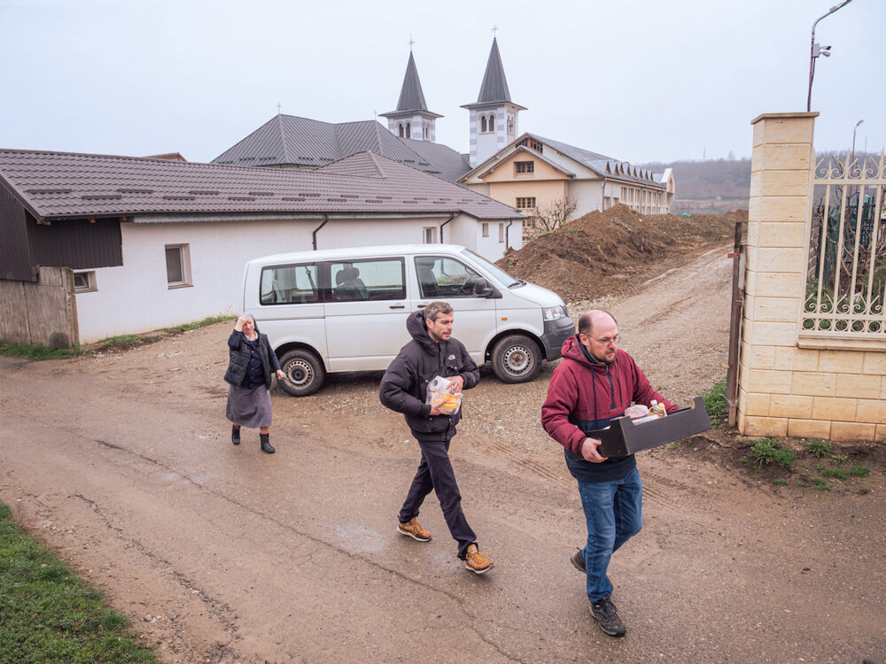 L'équipe de Ouest-Est pendant une distribution. La famille que nous visitons vit dans un taudis frôlant la ruine, alors que le quartier s'enrichit rapidement : juste en face, une grande maison avec une plaque annonçant une entreprise de commerce international. Le contraste est saisissant.
